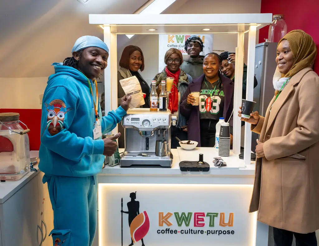 Antony of Kwetu Coffee at his coffee stand with smiling workshop attendees holding cups